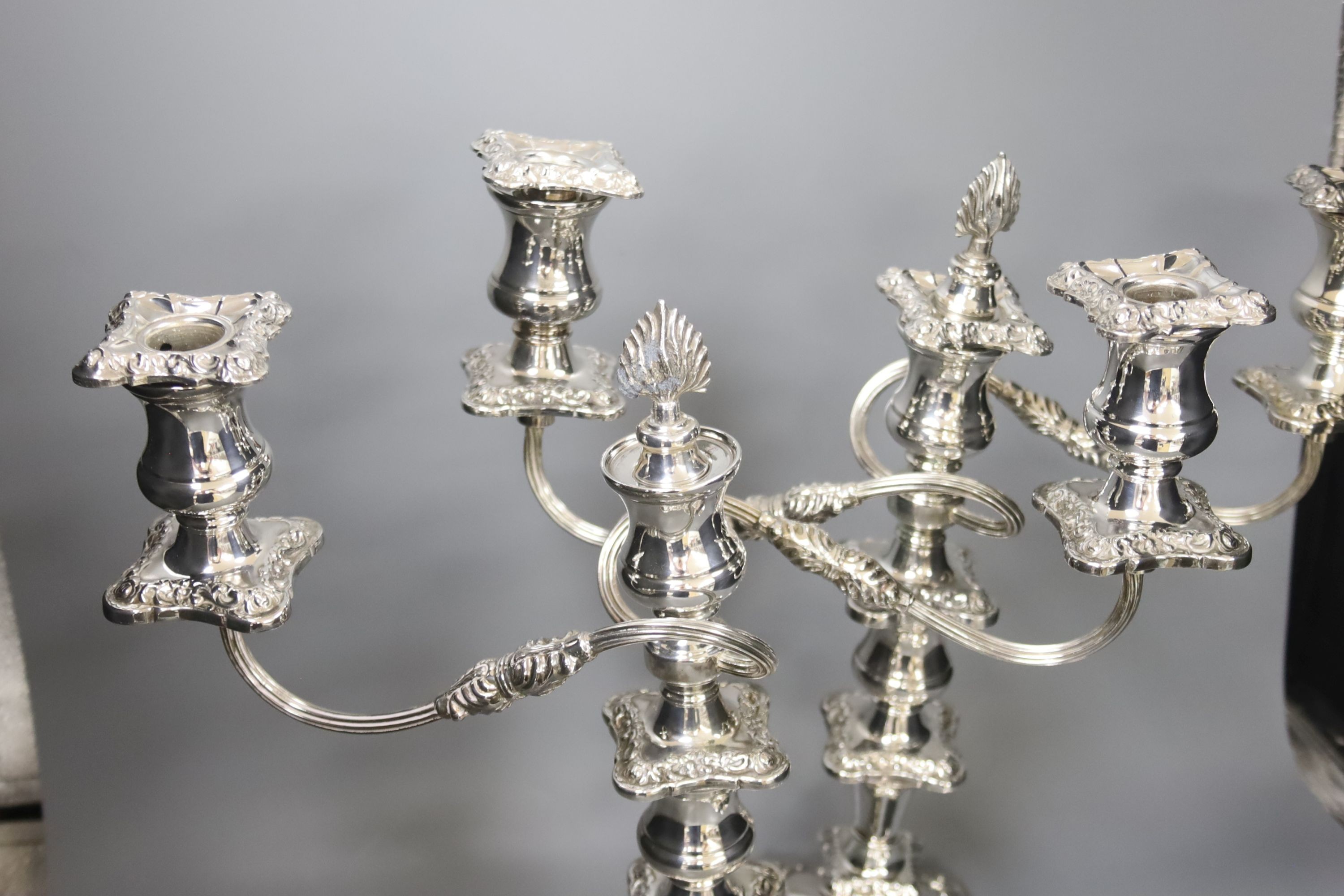 A pair of silver plated candelabra, two plated salvers and two plated mustard pots